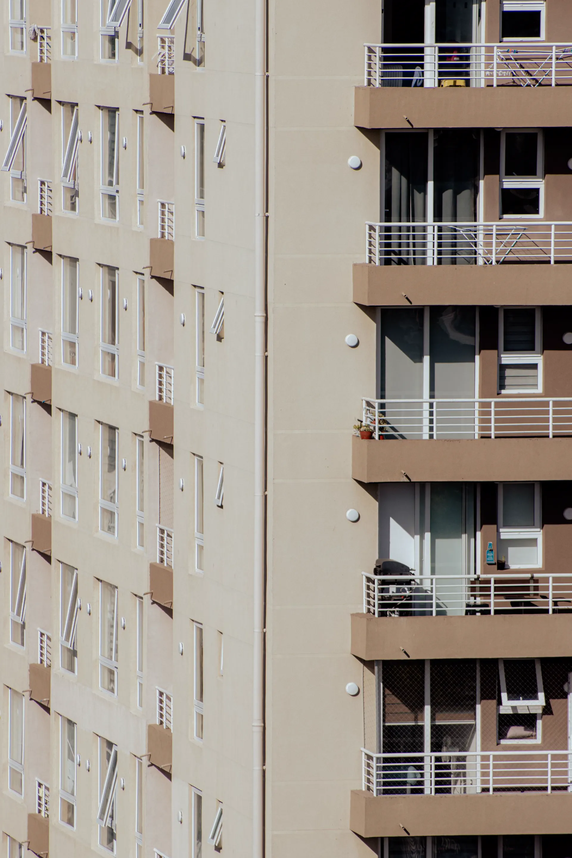 Facade of a low-rise residential apartment building with rows of planted balconies